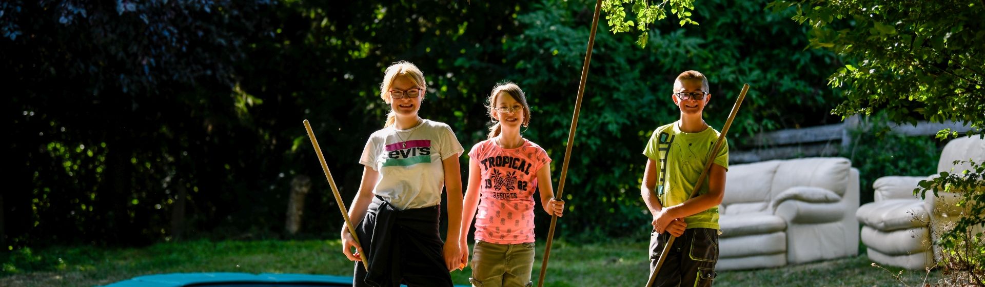 3 Kinder im Garten mit Gartengeräten