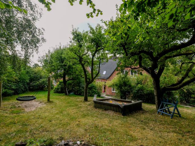 Garten der WG Blumenthal mit Sandkiste und Schaukel, das Haus im Hintergrund