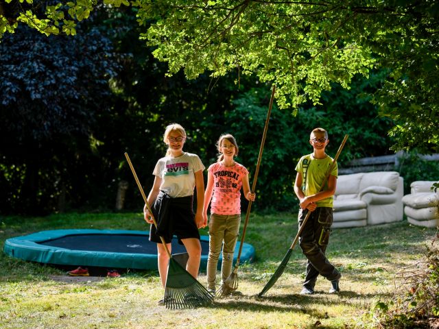 3 Kinder im Garten mit Gartengeräten