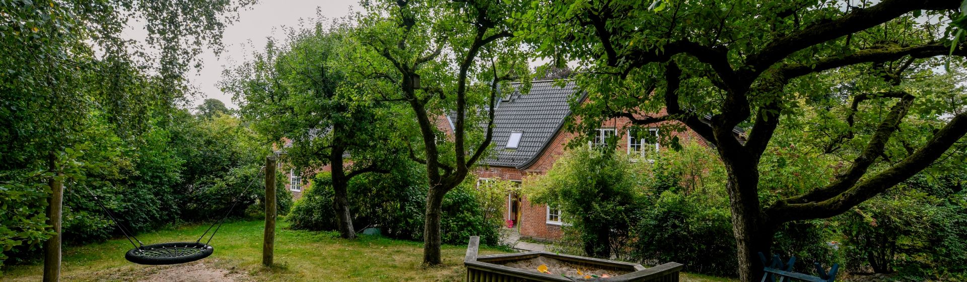 Garten der WG Blumenthal mit Sandkiste und Schaukel, das Haus im Hintergrund